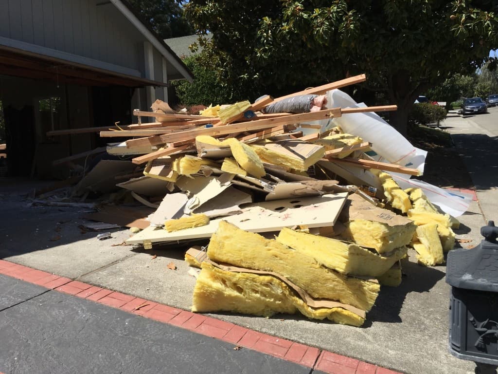 Pile of construction debris including lumber, drywall, and insulation ready for removal
