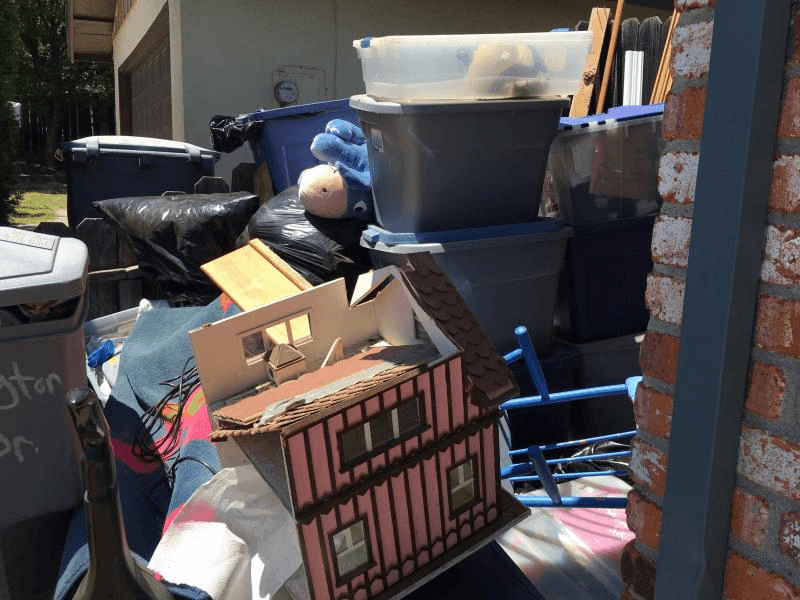 Property cleanout with bins, bags, and mixed household items piled outside