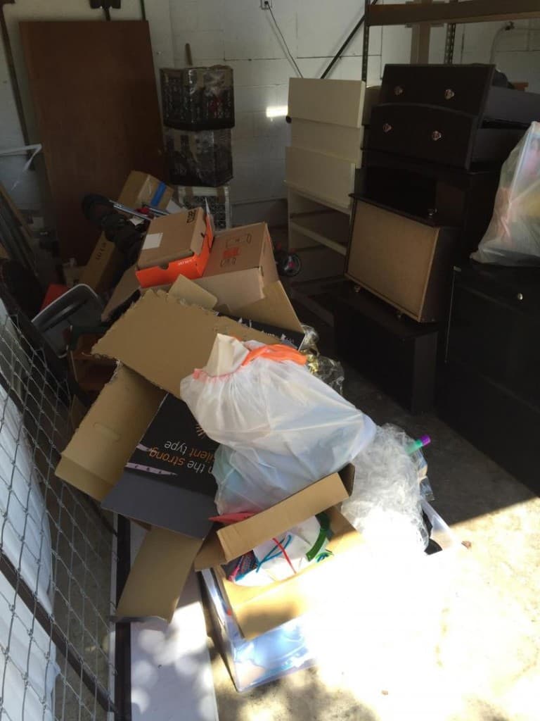 Cluttered storage unit with boxes, furniture, and bags ready for cleanout